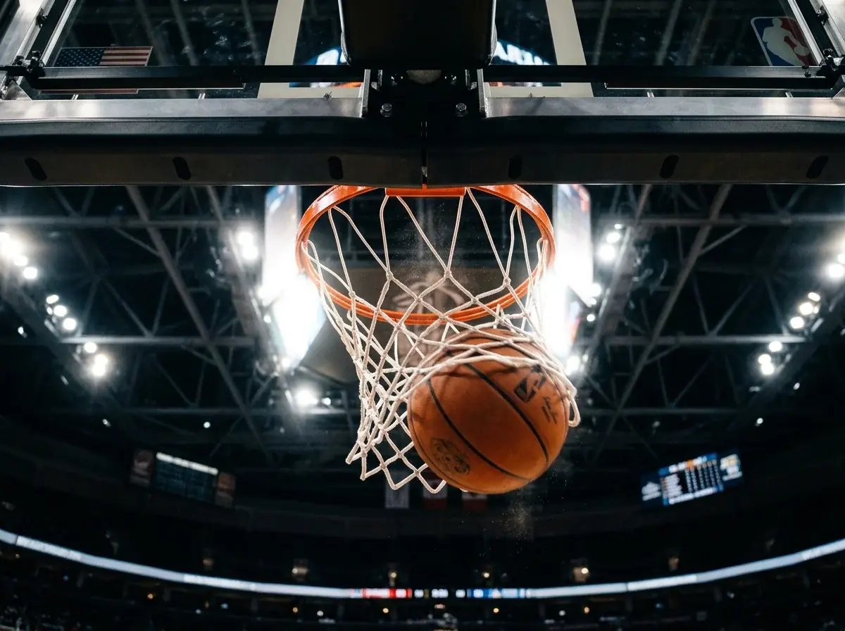 Basketball going through hoop with scoreboard showing game totals